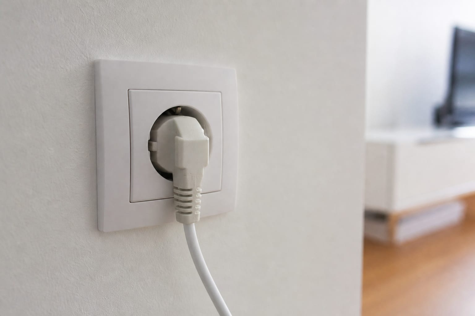 Prise électrique murale avec une fiche branchée, gros plan sur le mur d'un intérieur domestique