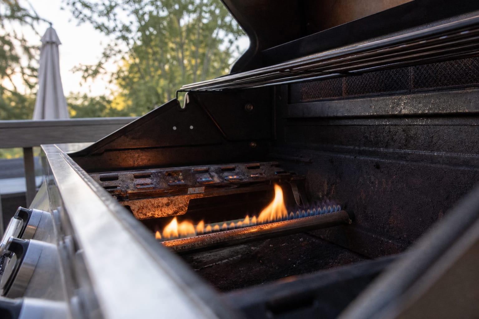 Brûleur de barbecue à gaz allumé en gros plan, flamme visible sur une terrasse extérieure