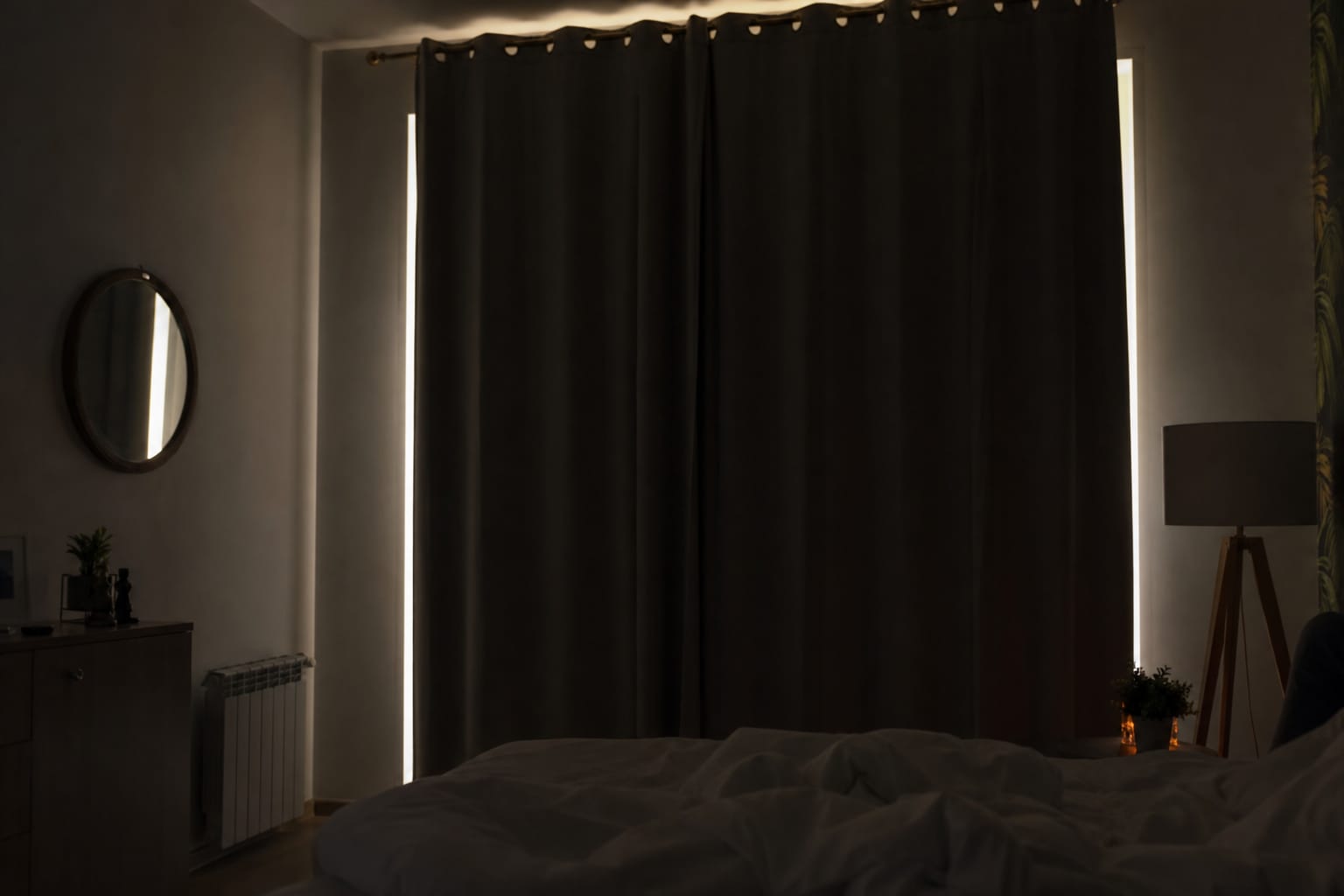Rideaux occultants fermés devant une fenêtre de chambre, filet de lumière visible sur le côté au petit matin